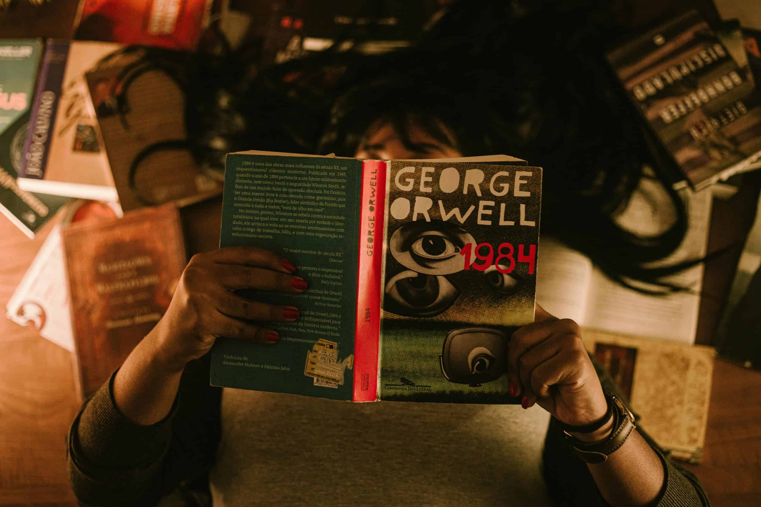dystopia novel 1984 george orwell book in the centre, girl holding it above her face