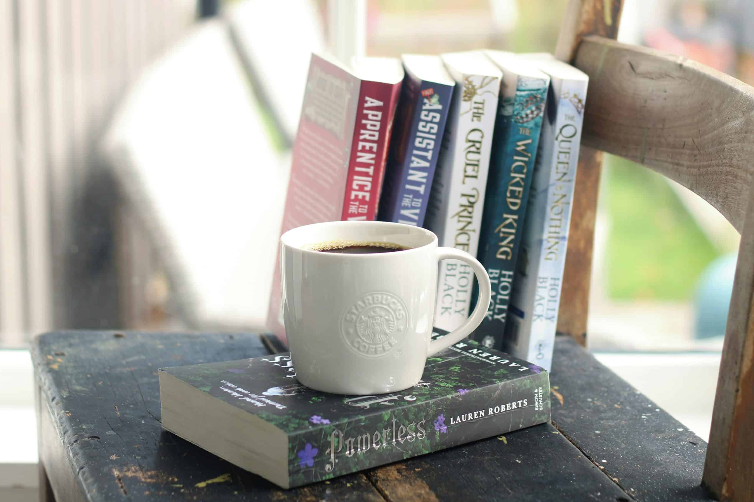 Book Lover’s Reading Nook Coffee cup and books on a rustic wooden table for book lovers.