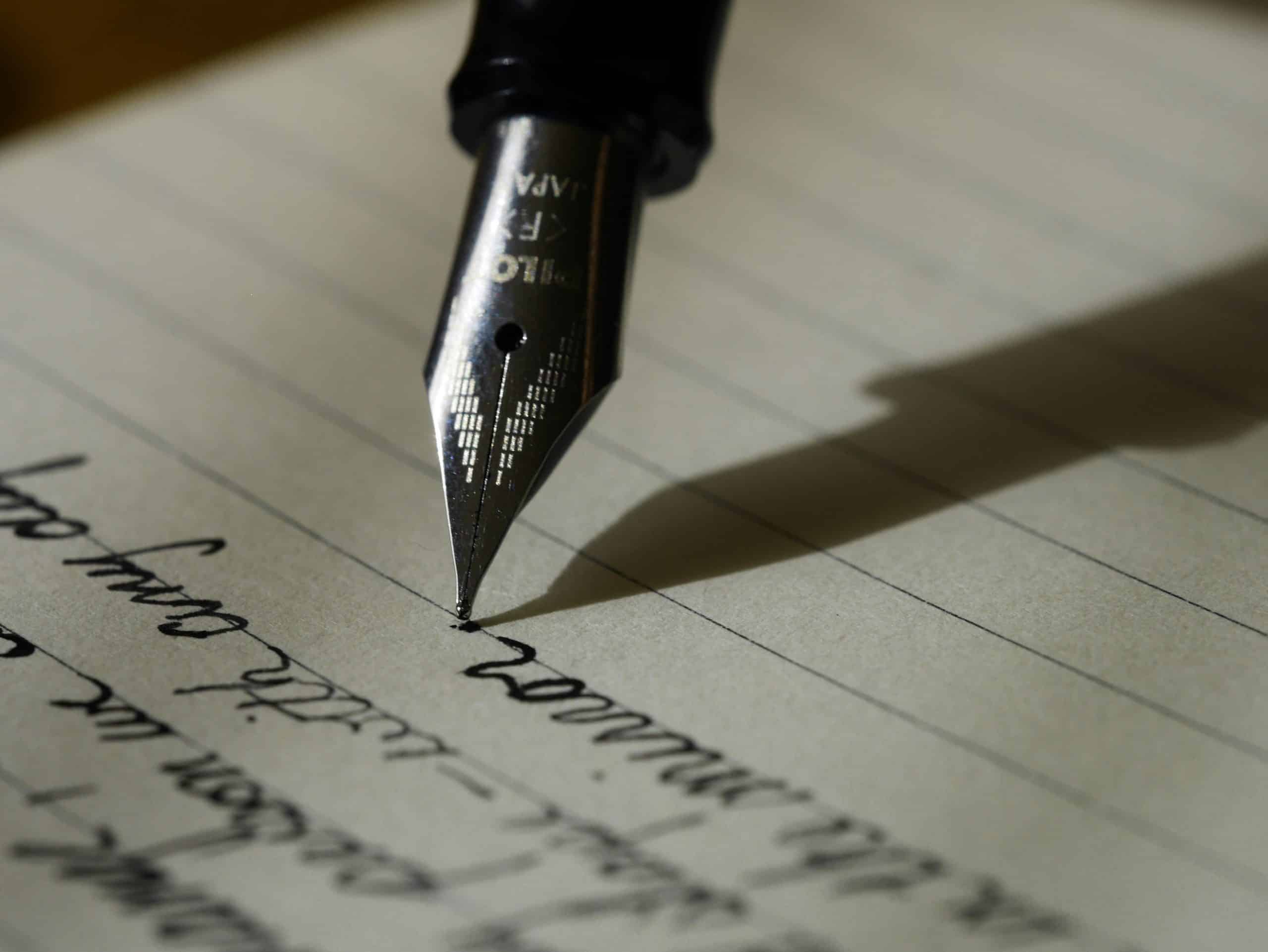 Creative Fountain Pen Writing Close-up of a fountain pen writing on lined paper with black ink.