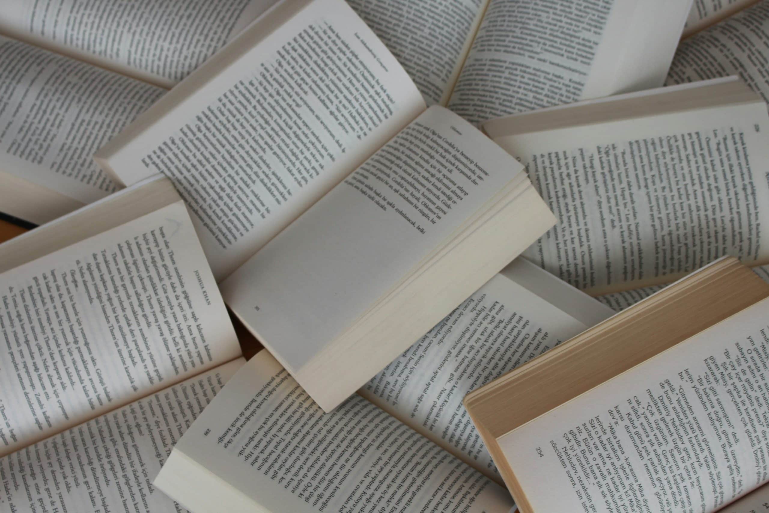 The Art of Crafting a Villain in Fantasy Writing An open book surrounded by multiple other books, creating a literary and fantasy-themed atmosphere.