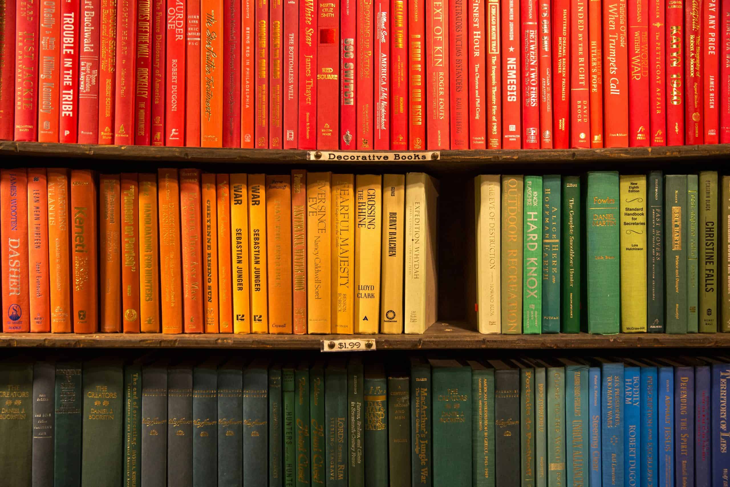 Books ordered by colour across three shelves, red to orange to green